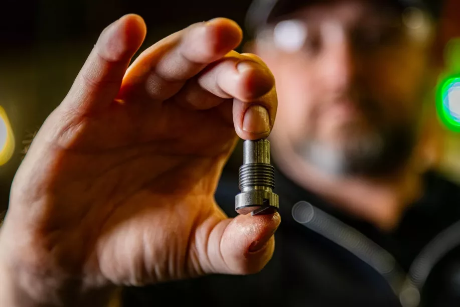 Jeremiah-Hold-Piece-min A man holding a custom fabricated metal part