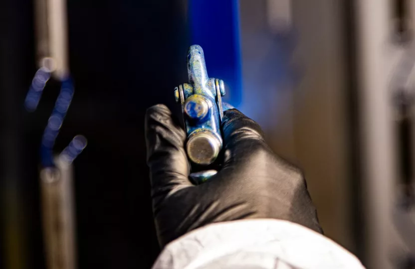 Gloved hand spray painting a metal piece
