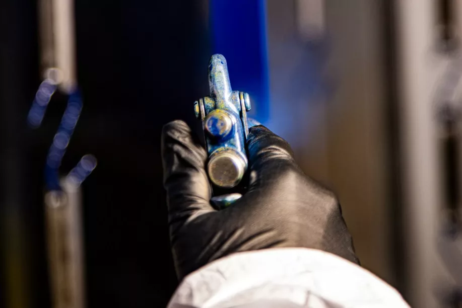 Painting-min Gloved hand spray painting a metal piece